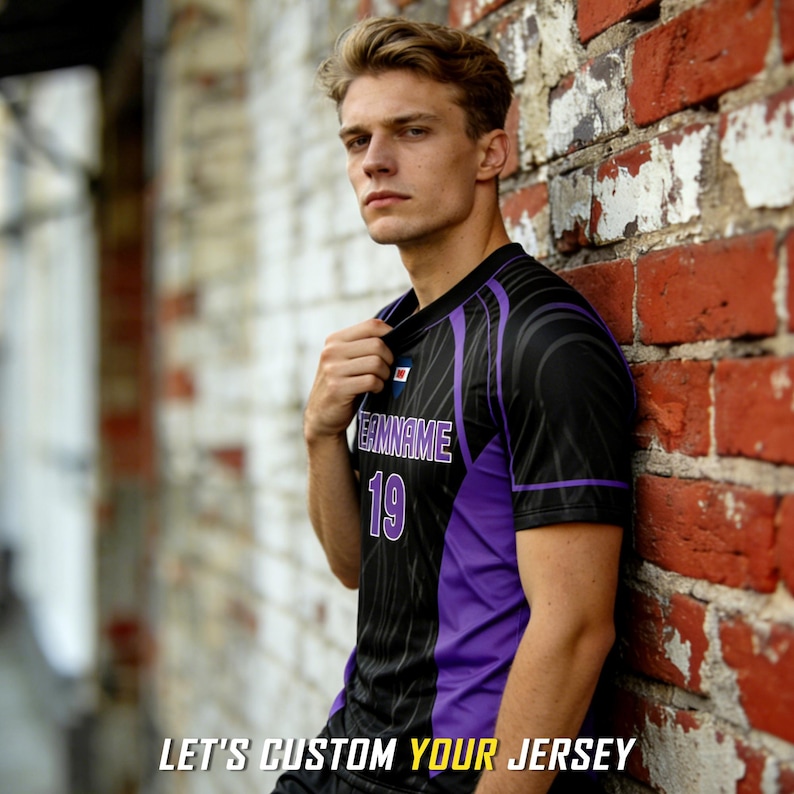 May include: A black and purple short-sleeved jersey featuring a V-neck collar, the text "TEAMNAME" in white with purple outlines, the number "19" in white with purple outlines, and a small rectangular logo on the chest. Text reads: LET'S CUSTOM YOUR JERSEY.