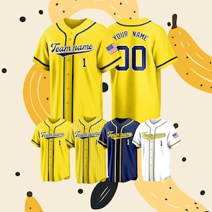 Può includere: Una collezione di maglie da baseball a maniche corte in giallo, blu navy e bianco. Le maglie presentano chiusure frontali con bottoni, bordini blu scuro e la scritta Team name con il numero 1. Alcune includono una piccola bandiera americana.