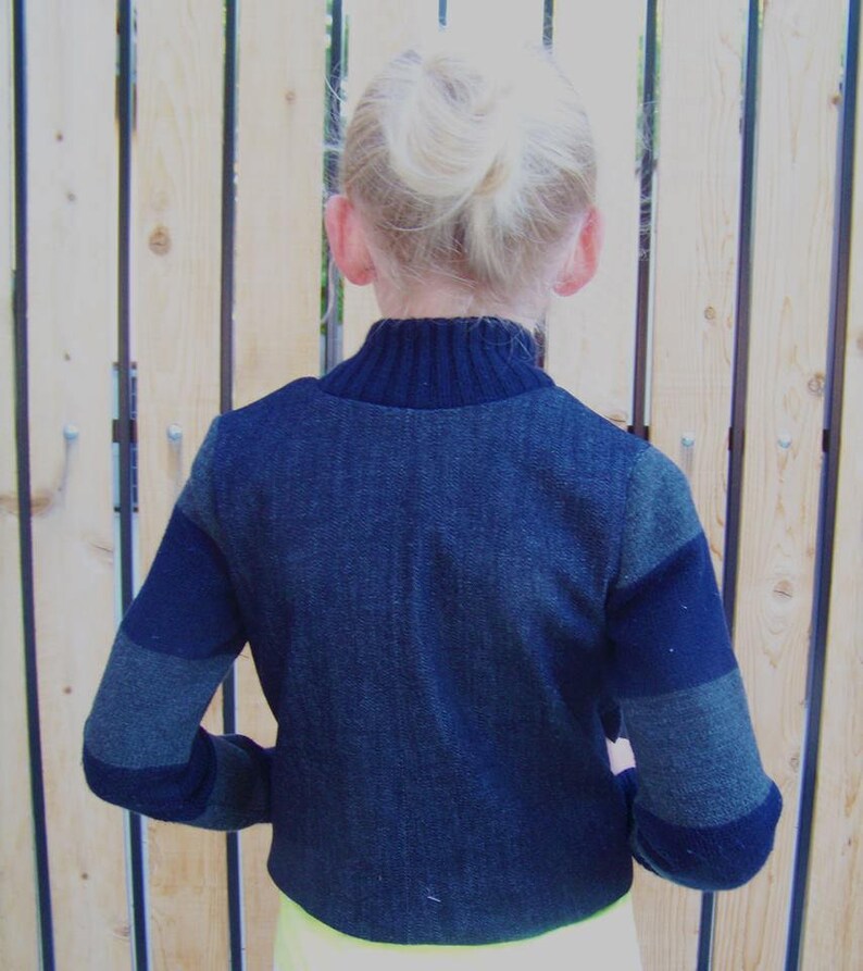 May include: A dark blue sweater with grey and black stripes on the sleeves. The sweater has a mock neck and is cropped.