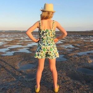 Puede incluir: Una persona joven con un sombrero de paja y un vestido de verano con estampado floral se encuentra de pie en una playa fangosa. La persona est&aacute; de espaldas a la c&aacute;mara y tiene las manos en las caderas.