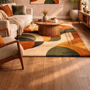 May include: A living room scene featuring a beige sofa with orange and green throw pillows, a wooden coffee table, and a patterned rug with geometric shapes in orange, green, and beige. A wooden chair and a cabinet are also visible.