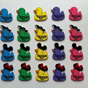 May include: A collection of colorful rubber ducky charms in various colors, including blue, green, yellow, purple, and pink. Some ducks have pirate hats, mouse ears, or bows. Each duck has the word "TREASURE 2025" printed on it.