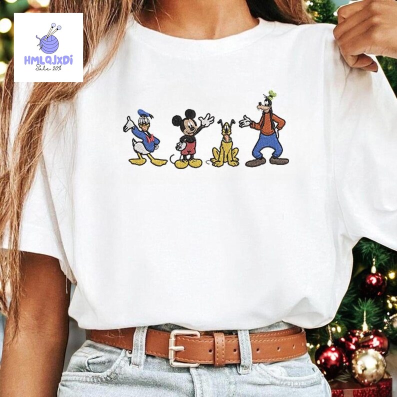 A white t-shirt with a graphic design of Disney characters Mickey Mouse, Donald Duck, and Goofy.