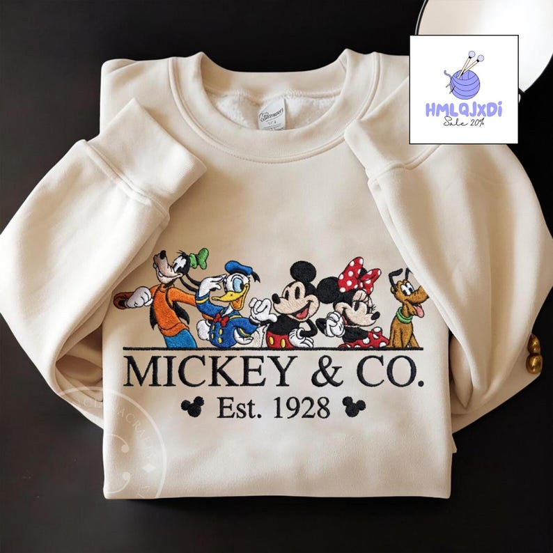 A white sweatshirt with a graphic design featuring Disney characters Mickey Mouse and Donald Duck, along with the text "MICKEY & CO. Est. 1928".