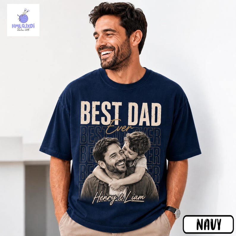 A man wearing a navy blue t-shirt with a graphic design featuring a smiling father embracing his son.