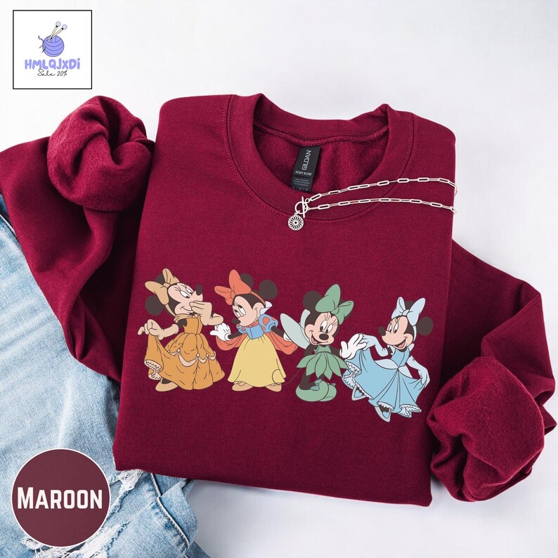 A red sweater with a graphic of four Disney Minnie Mouse characters, including Snow White and the Seven Dwarfs, printed on it.