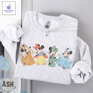 A gray sweatshirt with a graphic of four Disney characters, including Minnie Mouse, Snow White, Cinderella, and other well-known characters from the Disney film series.