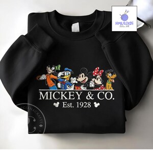 A black sweatshirt with a graphic design featuring Mickey Mouse and Donald Duck, along with the text "MICKEY & CO. Est. 1928".