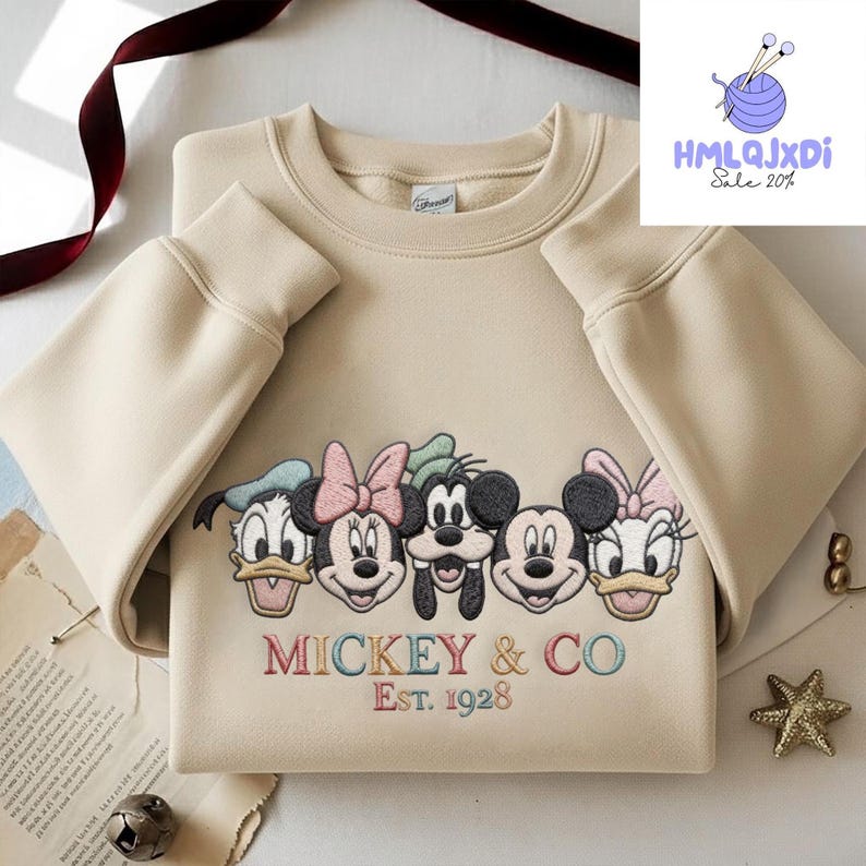 A beige sweater with a graphic design featuring the faces of Disney characters Mickey Mouse and Co.