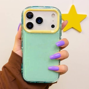 以下が含まれることがあります： ミントグリーンと黄色の携帯電話ケース。透明でテクスチャ加工されたボーダーが付いています。ケースには、3つのレンズとフラッシュを備えたカメラの切り抜きがあります。紫色の爪をした人が携帯電話ケースを持っています。