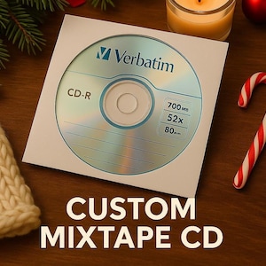 May include: A CD-R disc in a white paper sleeve with the text "Verbatim" and "CD-R". The disc has a capacity of 700MB, a speed of 52x, and a diameter of 80mm. The text "CUSTOM MIXTAPE CD" is at the bottom.