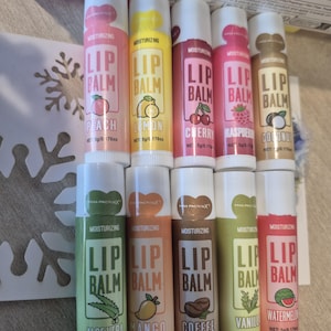 Op de afbeelding: Assortiment van hydraterende lippenbalsems in diverse smaken, waaronder perzik, citroen, kers, framboos en kokosnoot. Elke tube is gelabeld met de smaak en merknaam. Nettogewicht: 5g/0,176oz.
