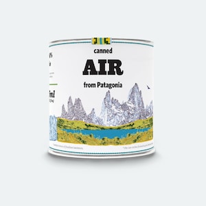 Può includere: Una lattina bianca con un'immagine blu e verde di montagne e un lago. La lattina dice "canned AIR from Patagonia".