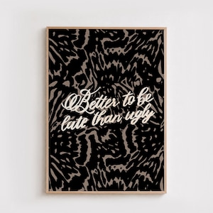 May include: A rectangular wall art print in a light wood frame featuring a black and beige abstract wavy pattern. The text Better to be late than ugly is written in a white cursive script font across the center of the graphic design.