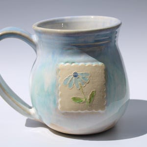Taza de cerámica hecha a mano con emblema bordado.