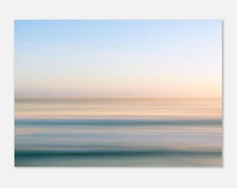May include: Abstract landscape art print featuring blurred horizontal lines of blue, teal, and peach hues, evoking a sense of the ocean and sky. The artwork has a soft, dreamy quality, with a gradient of colors from top to bottom.