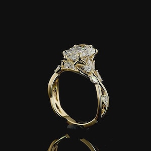 Puede incluir: Un anillo de compromiso de oro con una gran piedra central de diamante de talla ovalada. El anillo presenta diamantes de acento m&aacute;s peque&ntilde;os y una banda decorativa. El anillo est&aacute; sobre un fondo negro.