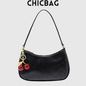 May include: Black baguette handbag with a single shoulder strap. The bag features a gold zipper and a cherry charm. The text "CHICBAG" is at the top of the image.