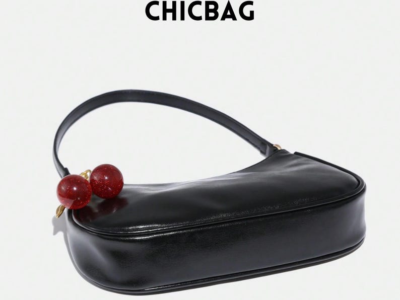 May include: Black shoulder bag with a curved design and a single handle. The bag features a cherry charm with red and gold accents. The word "CHICBAG" is printed at the top.
