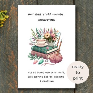 May include: A white print with the text "HOT GIRL STUFF SOUNDS EXHAUSTING" and "I'LL BE DOING OLD LADY STUFF, LIKE SIPPING COFFEE, READING & CRAFTING." The image includes a stack of books, a teacup, flowers, and yarn.