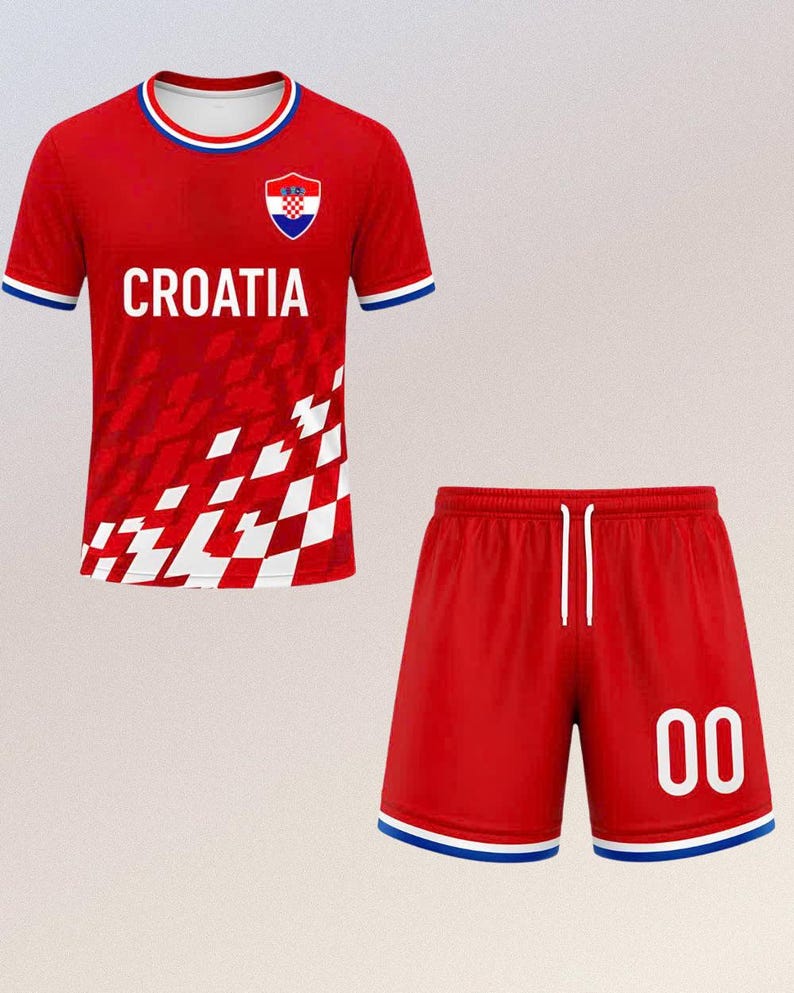 以下が含まれることがあります： クロアチアの赤いサッカーユニフォームセット。ジャージには白い「CROATIA」の文字、クロアチアの紋章、白と赤のチェック柄があります。ショーツは赤色で、数字「00」が白で表示されています。