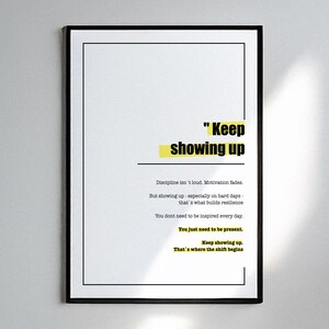 Könnte beinhalten: Ein gerahmter Druck mit dem Text "Keep showing up" in fetter Schrift, hervorgehoben durch gelbe Rechtecke. Der Druck enthält motivierenden Text über Disziplin und Belastbarkeit, vor weißem Hintergrund.