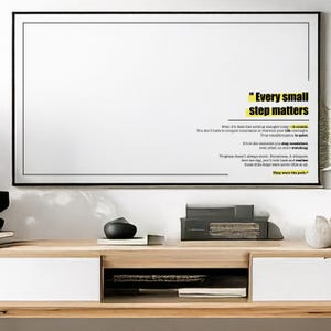 Könnte beinhalten: Ein gerahmtes weißes Poster mit schwarzem Rand zeigt das Zitat "Every small step matters" in gelbem und schwarzem Text. Zusätzlicher Text darunter erläutert das Thema Ausdauer und Fortschritt. Das Poster hängt über einem Holzschrank.