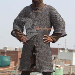 May include: A chainmail shirt, a type of medieval armor, is displayed. The shirt is made of small, interlocking metal rings, creating a flexible yet protective garment. The shirt has long sleeves and a split front.