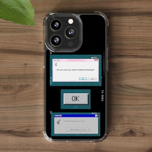 Può includere: Una custodia trasparente per telefono con retro nero con un design di finestre di messaggi di errore del computer retrò. I messaggi includono "Sei sicuro di voler cancellare tutti i sentimenti?" e "Dove abbiamo sbagliato?"