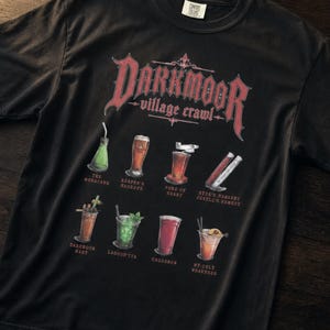 May include: A black short-sleeve t-shirt featuring a red graphic with the text Darkmoor Village Crawl. Below the text are eight illustrations of various drinks with labels including The Morado, Reaper's Reserve, Pure of Heart, and Jekyll's Remedy.