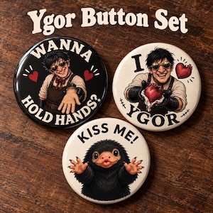 May include: A set of three circular buttons titled Ygor Button Set. One black button features a character with goggles asking WANNA HOLD HANDS? One white button shows the same character holding a heart with I LOVE YGOR. One white button features a furry creature with the text KISS ME!