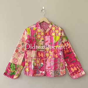 May include: A long-sleeved quilted jacket featuring a vibrant patchwork design in shades of pink, yellow, and green with various floral and geometric patterns. The jacket has a button-front closure, a collar, and two front pockets. Text reads Oldtextilecraft?