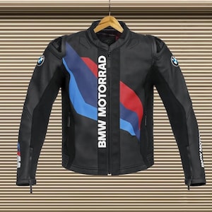 May include: Black motorcycle jacket with the BMW Motorrad logo in white. The jacket has blue and red stripes on the front and BMW logos on the sleeves. The jacket is hanging on a wooden hanger.