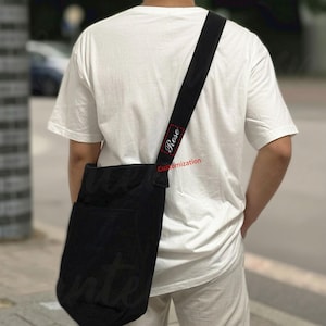 May include: Black messenger bag with a wide shoulder strap. The strap has the word "Rose" in a red rectangle and the word "Customization" below it. The bag is worn over the shoulder.