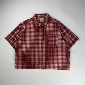 Puede incluir: Camisa de manga corta a cuadros rojos y blancos, con cuello abotonado y bolsillo en el pecho. La camisa tiene un patrón de cuadros clásico y un ajuste relajado. Fabricada con un tejido suave y cómodo.