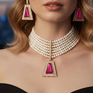 Puede incluir: Un collar de perlas de varias hebras con un colgante de oro con una piedra rosa y detalles de diamantes. También se ven pendientes de oro a juego con piedras rosas y detalles de diamantes. La joyería está sobre un fondo negro.