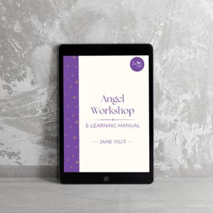 Peut inclure: Une tablette noire affiche la couverture d'un manuel d'apprentissage en ligne intitulé "Angel Workshop". La couverture est blanche avec des accents et du texte violets. Le nom de l'auteur, Jane Yigit, est également visible. La tablette est posée sur un fond texturé gris.