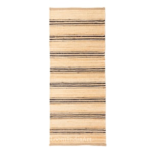 May include: A rectangular jute rug with horizontal black stripes. The rug has a natural beige color with dark brown stripes. The rug is made of woven jute material. The rug is suitable for indoor use.