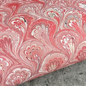 May include: A fabric featuring a marbled pattern with repeating fan-shaped motifs in shades of coral pink, white, and black. The design consists of fluid, swirling lines that create a dense, layered effect across the entire surface of the material.