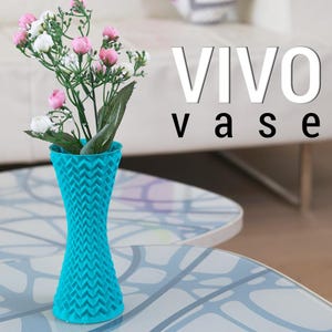 May include: A turquoise vase with a textured zigzag pattern, holding a bouquet of pink and white flowers with green leaves. The word "VIVO" and "vase" are displayed in white and black text.