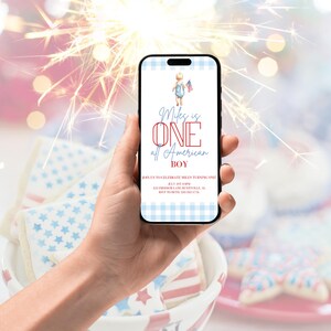 May include: A smartphone displays a digital invitation with a patriotic theme. The invitation reads "Miles is ONE all American BOY" with a watercolor illustration of a child holding a flag. The phone is held in a hand, with cookies in a bowl in the foreground.