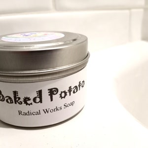 May include: A silver tin with a white label that reads "Baked Potato" and "Radical Works Soap".