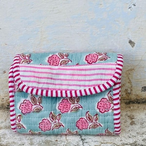 Peut inclure: Un portefeuille matelassé à motifs floraux. Le portefeuille présente un fond bleu clair avec des fleurs roses et des feuilles marron. Le rabat et les bords sont ornés de rayures roses et blanches.
