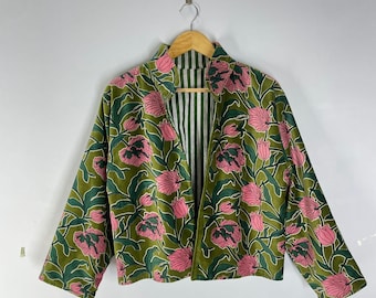 Op de afbeelding: Een open jasje met bloemenpatroon. De jas heeft een groene achtergrond met roze bloemen en groene bladeren. De binnenvoering heeft een wit en groen gestreept patroon. De jas hangt aan een houten hanger.