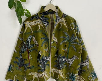 Könnte beinhalten: Olivgrüne Samtjacke mit durchgehendem Reißverschluss. Die Jacke hat ein Dschungel-Thema mit Geparden, Zebras, Vögeln und Palmen. Die Jacke hat einen hohen Kragen und lange Ärmel.