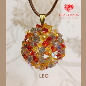 May include: A round pendant necklace with a gold-colored bail and a brown cord. The pendant is a sphere made of red, yellow, and clear crystals. The word "LEO" is at the bottom of the image. The text "HEARTMADE by Carme Grau" is in the upper right corner.