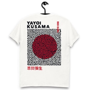 Puede incluir: Camiseta blanca con un diseño gráfico rojo y negro. El diseño incluye el texto "YAYOI KUSAMA", caracteres japoneses, un círculo rojo y un patrón de líneas negras y blancas. También se ve el texto "TOKYO 1998".