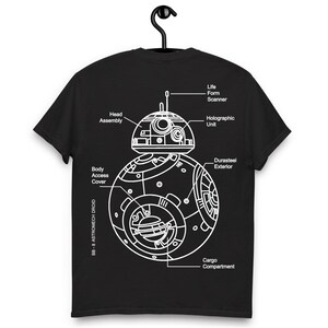 Pode incluir: Camiseta preta com um esquema branco do droide Astromech BB-8. O design inclui etiquetas para a montagem da cabeça, a unidade holográfica e o compartimento de carga. A camiseta está pendurada em um cabide preto.