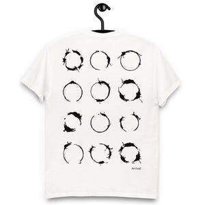 Pode incluir: Camiseta branca com um design gráfico preto de doze símbolos circulares. Os símbolos estão dispostos em três filas de quatro. A palavra "Arrival" está impressa em preto no canto inferior direito da camiseta.