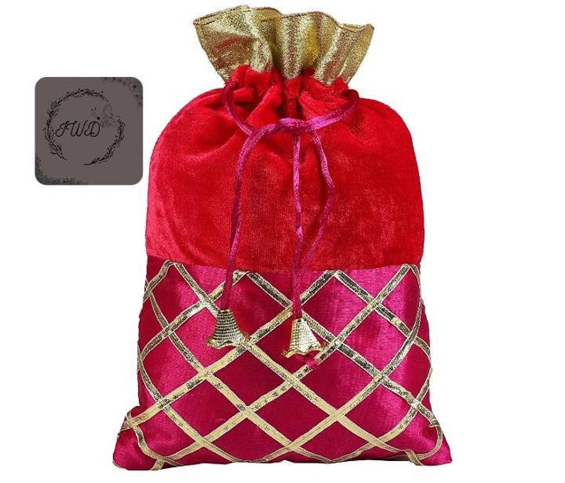 May include: A red velvet drawstring bag with a gold and pink diamond pattern on the bottom. The top of the bag is a gathered gold fabric. The bag has a drawstring closure with pink cords and gold bell charms.